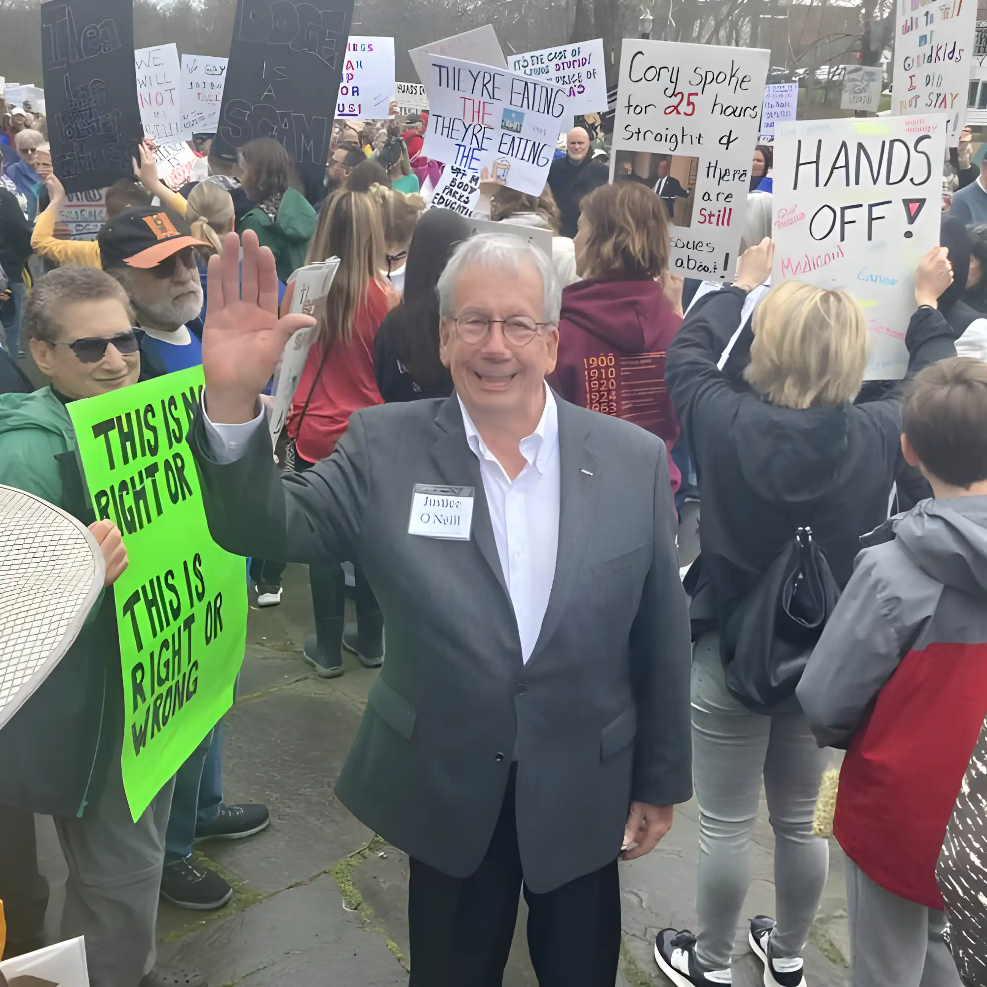 Bill O'Neill waving to the camera surrounded by a group of protestors.